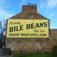 Load image into Gallery viewer, Brick building with a large yellow sign advertising 'Bile Beans' against a blue sky.